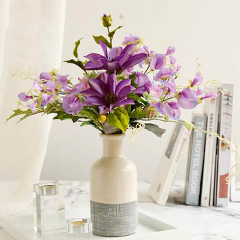 A bouquet of purple artificial flowers in a ceramic vase